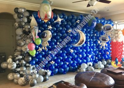 Space themed balloon wall with marbled organic garland to the left and jumbo foils of astronauts and spaceships