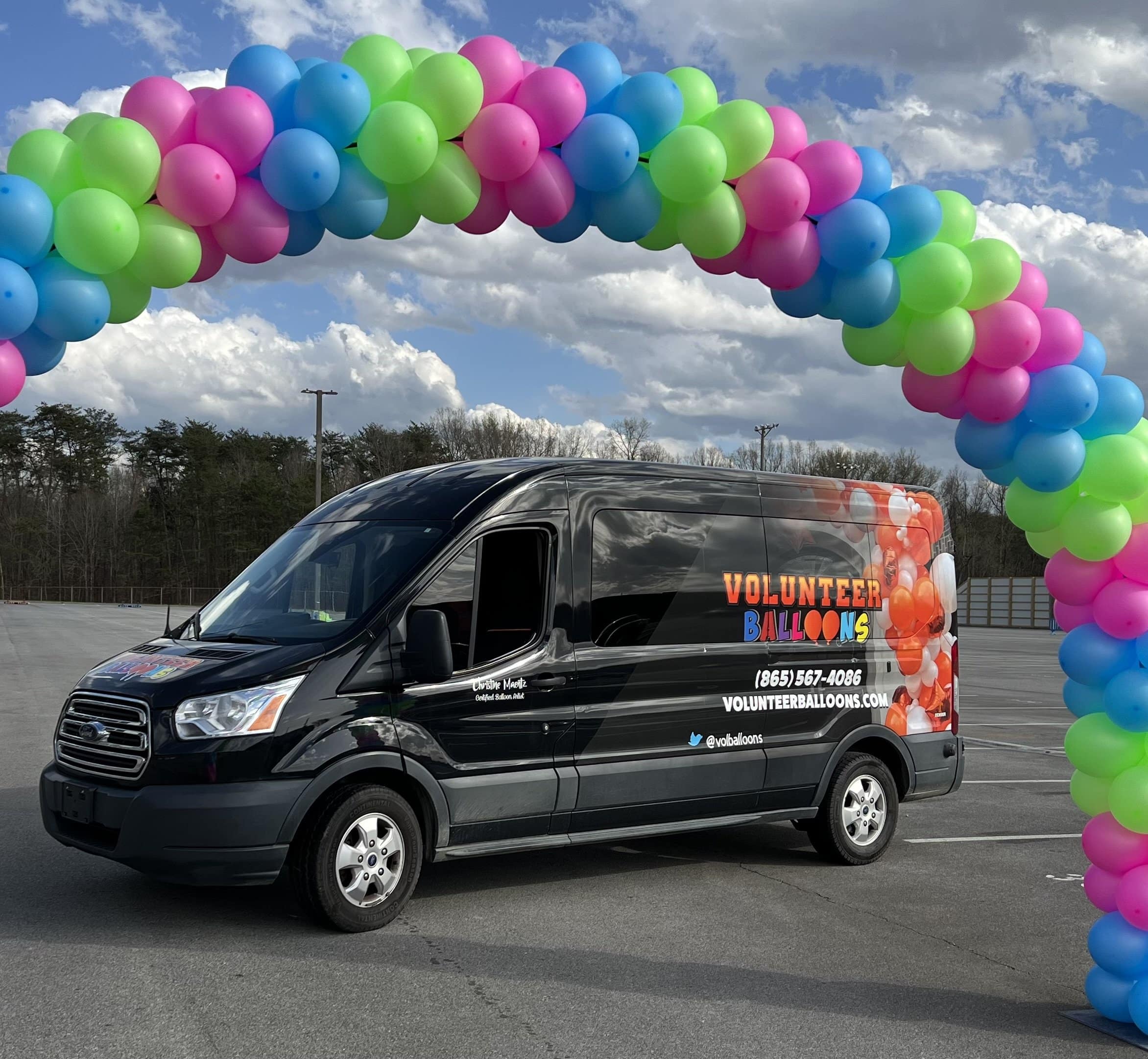 Service van with Volunteer Balloons printed on the side under a green blue and pink balloon arch