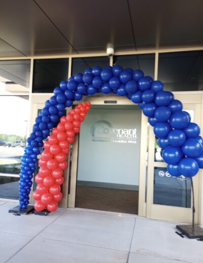 Covenant Health balloon arch in logo colors (blue and red) in front of double sliding doors