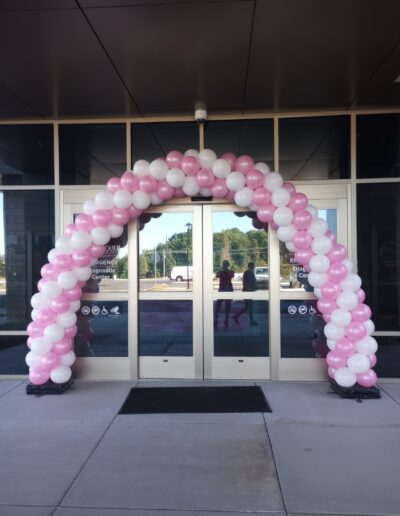 Spiral balloon arch in pink and white in front of double sliding doors outside Covenant Health business