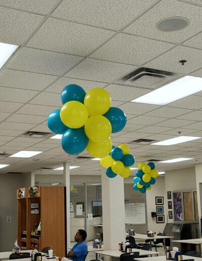 8 balloon clusters hanging from ceiling in office space in yellow and blue