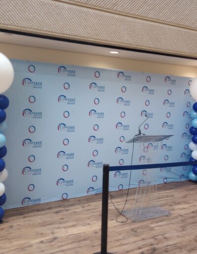 2 of our standard balloon columns in blue, light blue, and white placed on both sides of backdrop with "covenant health" logo on it