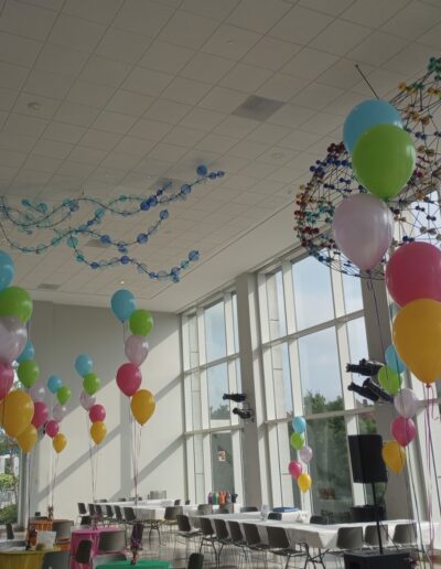 Staggered multi-colored balloon bouquets in large open museum space