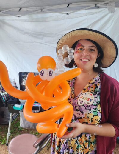 Woman holds balloon twisted octopus with butterfly paint on right eye