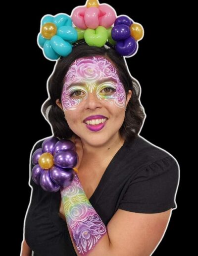 Woman with face paint on arm and face with a balloon flower crown and balloon flower wrist band